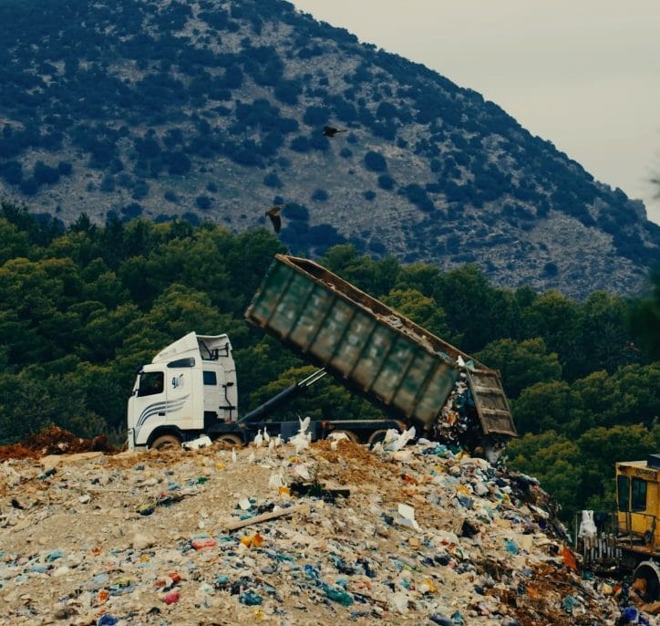 A collection truck unloading organic waste at a landfill site